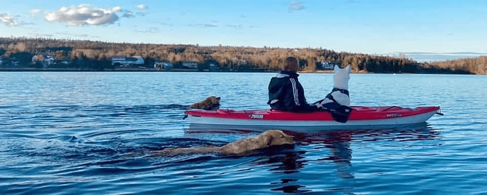 woman on a red and white canoe with her 3 rescue dogs - AKR community member